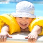 very young child in pool with blow up arm floats